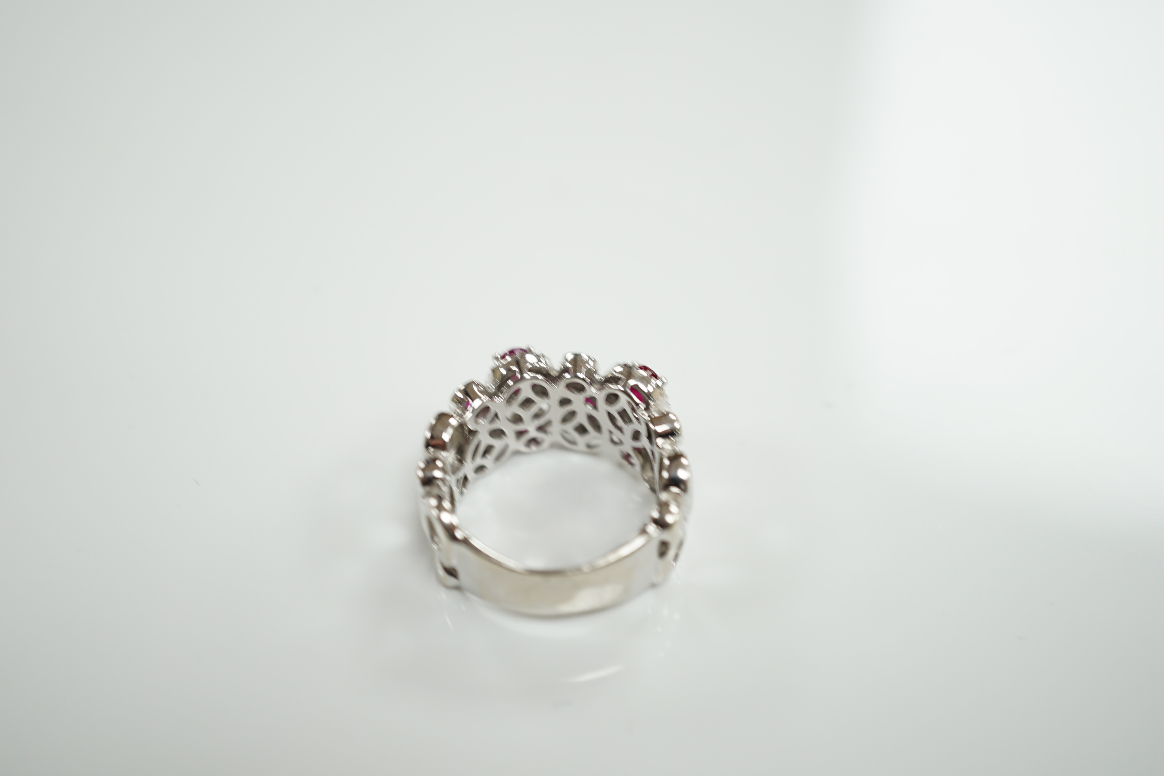 A modern 14ct white gold, ruby and diamond set multi cluster half hoop dress ring, size O, gross weight 8.1 grams.